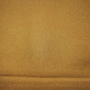 A solid caramel colour on a surface with natural slubs and irregular threads, very characteristic of linen.