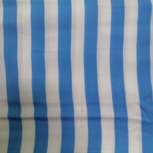 The perriwinkle fabric features a uniform stripe pattern consisting of even spaced, vertical white lines running parallel to one another.