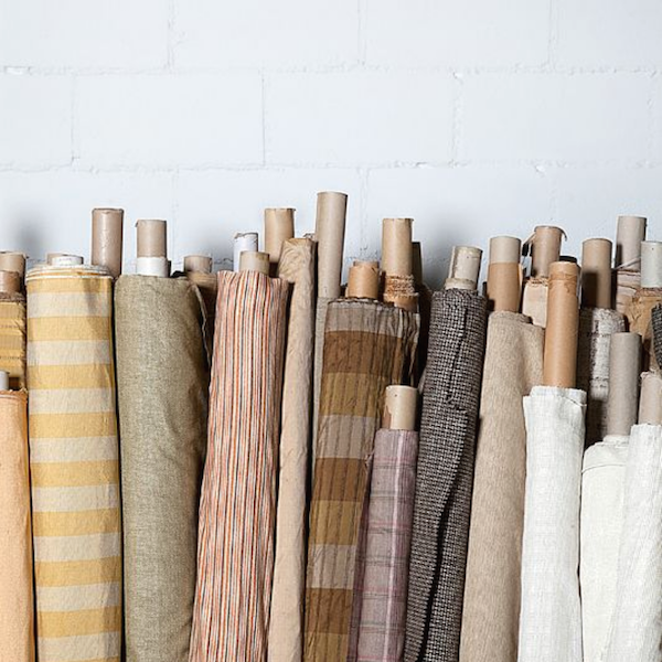 Multiple fabric rolls, leaning against a wall, with different stripe, texture or check designs