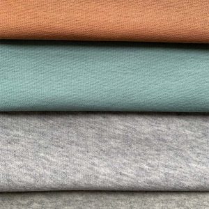 3 DIFFERENCT COLOURED FOLDED FABRICS STACKED ON TOP OF EACH OTHER