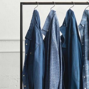 A CLOTHING RAIL WITH 4 DIFFERENT SHADE DENIM SHIRTS.