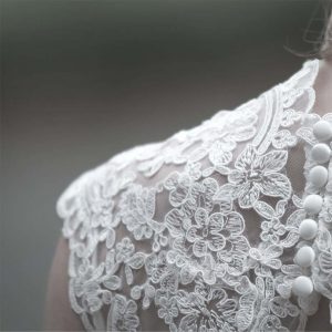 A WHITE TEXTURED LACE SLEEVE OR SHOULDER INSET.