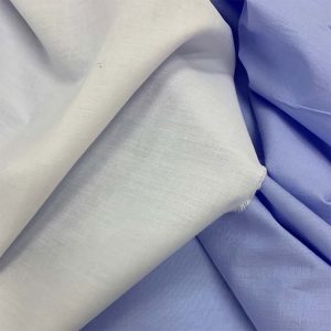 BLUE AND WHITE SHIRTING FABRIC DRAPED NEXT TO EACH OTHER.