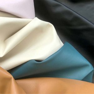 COLOURED PLEATHER FABRICS DRAPED NEXT TO EACH OTHER.