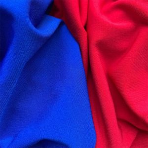 DIFFERENTLY COLOURED KNITTED FABRICS DRAPED NEXT TO EACH OTHER.