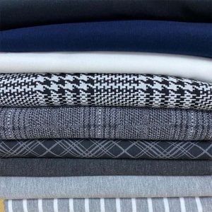 A STACK OF FOLDED PONTI FABRICS IN PLAIN, STRIPES AND WITH DIFFERENT PATTERNS.