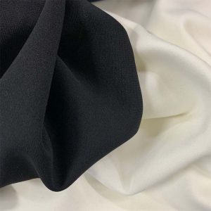 A BLACK AND A WHITE COLOUR KNITTED FABRICS DRAPED NEXT TO EACH OTHER.