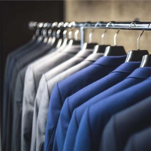 A CLOTHING RAIL WITH TAILORED JACKETS DISPLAYED AND SORTED IN MATCHING COLOURS.