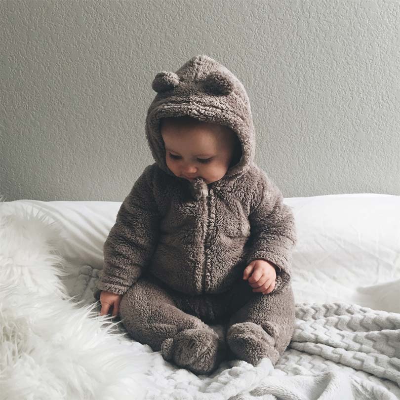 Sitting baby dressed in mocca colour fleece babygrow.