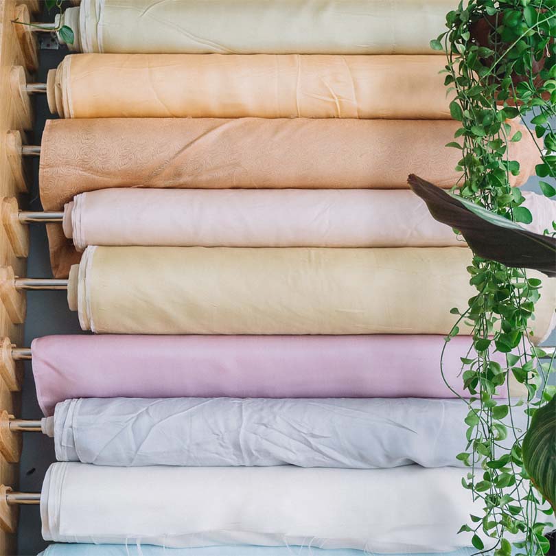 8 Pastel colour fabric rolls on display in a shop.