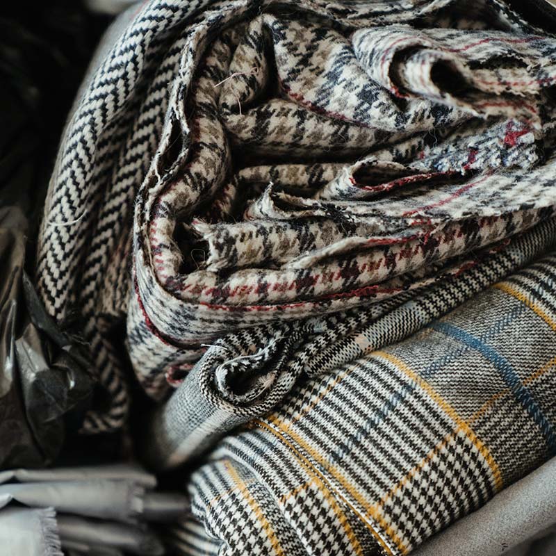 A stack of folded grey coloured fabrics with different check and stipe designs.