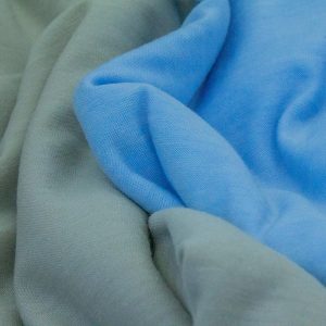 TONAL GREY AND BLUE KNITTED FABRICS DRAPED NEXT TO EACH OTHER.